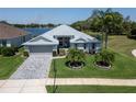Lakefront home featuring well-manicured lawn, lovely landscaping, and long paver driveway at 3723 Belle Rose Dr, Leesburg, FL 34748