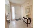 Inviting entryway featuring tile flooring, a decorative table, and a sidelight window beside the front door at 4387 Sambourne St, Clermont, FL 34711