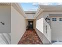 Front entryway with brick-paved walkway leading to a dark front door and white exterior at 4972 Big Cypress St, Oxford, FL 34484