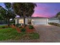 Charming single-story home with a brick driveway, mature landscaping, and a two-car garage at dusk at 4972 Big Cypress St, Oxford, FL 34484