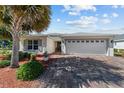 Inviting single-story home with landscaped yard, brick-paved driveway, and a two-car garage at 4972 Big Cypress St, Oxford, FL 34484