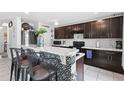 Modern kitchen featuring dark wood cabinets, a breakfast bar with patterned accents, and stainless steel appliances at 6401 Domenico Ct, Groveland, FL 34736