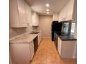Galley kitchen features stainless steel appliances, granite countertops and tile flooring at 677 Warner St, Groveland, FL 34736