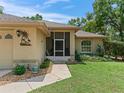 Close-up of home's entrance, featuring a screen door and manicured landscaping at 7260 Se 124Th Ln, Belleview, FL 34420
