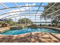 Screened-in pool area featuring brick pavers, a covered spa and an outdoor kitchen overlooking a lake at 848 Hawk Lndg, Fruitland Park, FL 34731