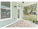 Covered porch with durable stone tile, calming green walls, and inviting view of the yard at 12129 Grand Oak Ln, Oxford, FL 34484