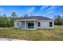 Backyard view of the house featuring a covered patio, sliding glass doors, and a well-maintained grassy area at 16374 Se 88Th Ave, Summerfield, FL 34491