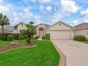 Charming single-story home featuring a meticulously landscaped yard, beige stucco, and a spacious two-car garage at 17930 Se 87Th Bourne Ave, The Villages, FL 32162