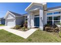 Inviting entryway of the house with a blue front door, manicured landscaping, and a clean walkway at 1922 Angel Fish Loop, Leesburg, FL 34748