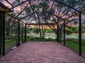 Large brick paved screened patio with overhead lighting looks out to lake and surrounding foliage at 2010 Otters Pond Rd, Fruitland Park, FL 34731