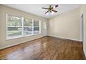 Bright living room featuring hardwood floors, ceiling fan, and large windows for natural light at 25519 Colmar Ave, Sorrento, FL 32776