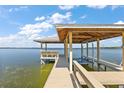 Lakeside dock featuring a covered seating area and a boat lift, perfect for enjoying waterfront activities at 38420 Langlois Pl, Leesburg, FL 34788