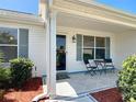 Inviting front porch with tiled flooring, seating area, and attractive landscaping at 508 Carrera Dr, The Villages, FL 32159
