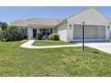 Well-manicured lawn, paved walkway, and green landscaping add charm to this quaint single story home at 508 Carrera Dr, The Villages, FL 32159