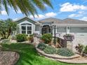 Beautiful single-story home with an expansive, landscaped front yard, colorful flowerbeds, and a paver driveway at 575 Wheelock St, The Villages, FL 32163