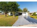Attractive single-story home featuring a well-manicured lawn, mature trees, and an extended driveway at 728 Tangerine Dr, The Villages, FL 32159