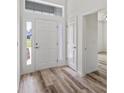 Welcoming entryway featuring a stylish front door, sidelight window, and attractive wood-look flooring at 8742 Se 158Th Pl, Summerfield, FL 34491