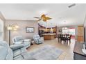 Open-concept living room with tile flooring, ceiling fan, and seamless flow to kitchen and dining area at 929 Eastmont Ct, The Villages, FL 32162