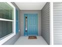 Inviting front porch with a charming blue door, shutter accents, and neutral siding at 947 Couture St, The Villages, FL 32163