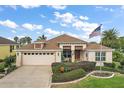 Charming single-Gathering home with a well-manicured lawn, an American flag, and an attached two-car garage at 1606 Mount Croghan Trl, The Villages, FL 32162