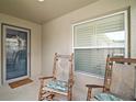 Inviting front porch with two rocking chairs, neutral paint, and a decorative wreath hanging on the front door at 1084 Becker Ave, The Villages, FL 32163