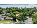 Aerial view of a home nestled amongst lush trees with a glimpse of the water in the distance at 1196 Lakeshore Dr, Mount Dora, FL 32757