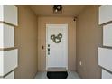 Close-up of the front door with decorative wreath, sidelights, and modern hardware in a welcoming entryway at 12340 Ne 48Th Loop, Oxford, FL 34484