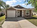 Charming single-Gathering home featuring an attached garage and a well-maintained lawn, under a sunny sky at 12340 Ne 48Th Loop, Oxford, FL 34484