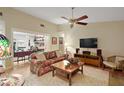 Spacious living room with vaulted ceiling, ceiling fan, hardwood floors and large TV at 20 Ginger Cir, Leesburg, FL 34748