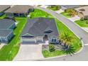 Aerial view of a well-manicured home in a neighborhood setting, highlighting its large roof and lush surroundings at 2006 Oppenheimer Ct, The Villages, FL 34762