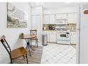 Cozy kitchen featuring white appliances and cabinets, a breakfast table, and light-colored tile flooring at 21707 Queen Mary Ct, Leesburg, FL 34748