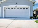 A pristine white garage door with decorative windows complements the manicured landscaping at 27018 White Plains Way, Leesburg, FL 34748