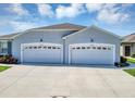 A well-lit two-car garage with white doors that matches the exterior of this lovely building at 27018 White Plains Way, Leesburg, FL 34748
