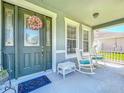 Inviting front porch with rocking chairs and a charming wreath adorning the front door at 2894 Southern Pines Loop, Clermont, FL 34711