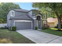 Two-story home featuring a well-manicured lawn, gray siding, white trim, and a two car garage at 30236 Pga Dr, Sorrento, FL 32776