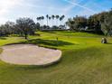 Scenic golf course view with sand trap, green, golfer, palm trees, and golf cart on a sunny day at 3785 Avon Ct, Clermont, FL 34711