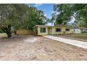 Inviting yellow home with tidy landscaping and a well-maintained front lawn and long driveway at 3972 Poinsettia Ave, Mount Dora, FL 32757