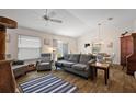 Comfortable living room featuring neutral tones, vaulted ceilings, and a ceiling fan above wood-look floors at 5817 Valente Ct, The Villages, FL 32163