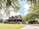 Charming home with wraparound porch, ramp, and covered parking area, surrounded by trees at 8091 C 476B, Bushnell, FL 33513