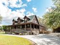 Home with wraparound porch, wood and stone siding, landscaped entrance, and concrete driveway at 8091 C 476B, Bushnell, FL 33513