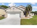 Charming home exterior featuring a well-maintained lawn and a two-car garage at 830 Palm Harbor Ct, Leesburg, FL 34748