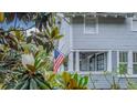 Charming home exterior showcasing a cozy covered porch with an American flag, framed by lush greenery at 908 N Tremain St, Mount Dora, FL 32757