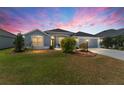 Beautiful home with a manicured lawn and lush landscaping at dusk at 1016 Pickering Path, The Villages, FL 32163