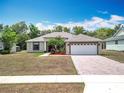 Inviting single-story home featuring a paved driveway, landscaping, and a two-car garage, creating curb appeal at 13546 Biscayne Grove Ln, Grand Island, FL 32735