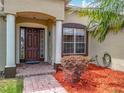 Inviting front entrance features a dark wood door, decorative columns, and a well-manicured garden at 13546 Biscayne Grove Ln, Grand Island, FL 32735