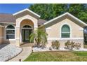 Inviting front entrance with decorative landscaping, enhanced by an arched doorway and decorative window at 14421 Pine Cone Trl, Clermont, FL 34711