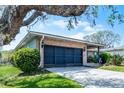 The home's garage and front entrance sit under a sprawling oak tree draped with Spanish moss at 16 Pine Run, Haines City, FL 33844