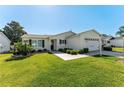 Well-kept home featuring green grass, a front lawn, a two-car garage, and light-colored siding at 17385 Se 76Th Champion Ave, The Villages, FL 32162