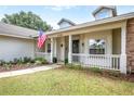 Inviting front porch with an American flag, decorative plants, and a classic white railing at 17728 Palm View Cir, Mount Dora, FL 32757