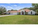 A well-kept single-story home with a lush green lawn, attached two-car garage, and a classic red front door at 17825 Whisperwind Dr, Clermont, FL 34715